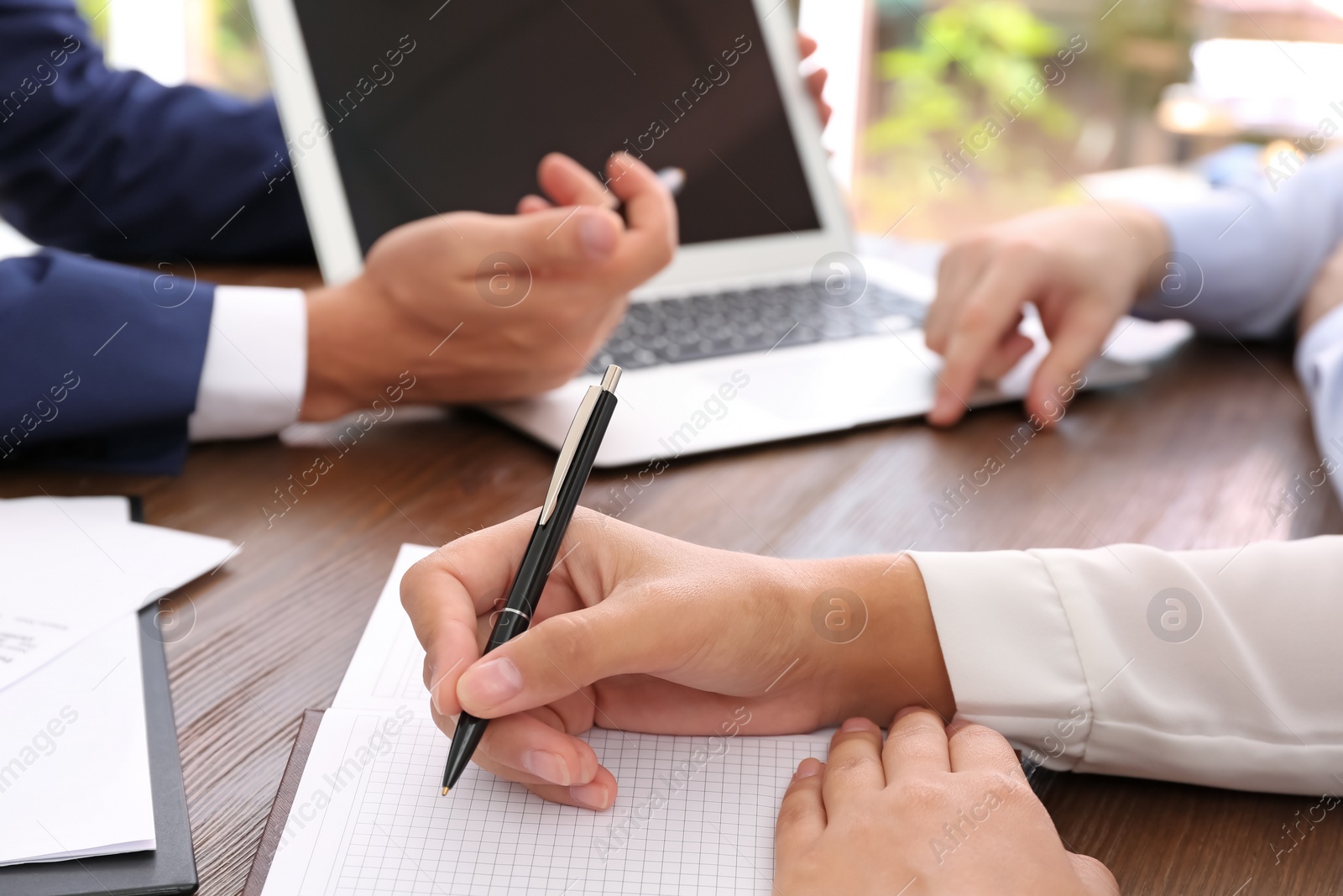 Photo of Lawyer working with clients at table in office, focus on hands