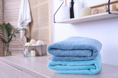 Stack of fresh towels on cabinet in bathroom. Space for text