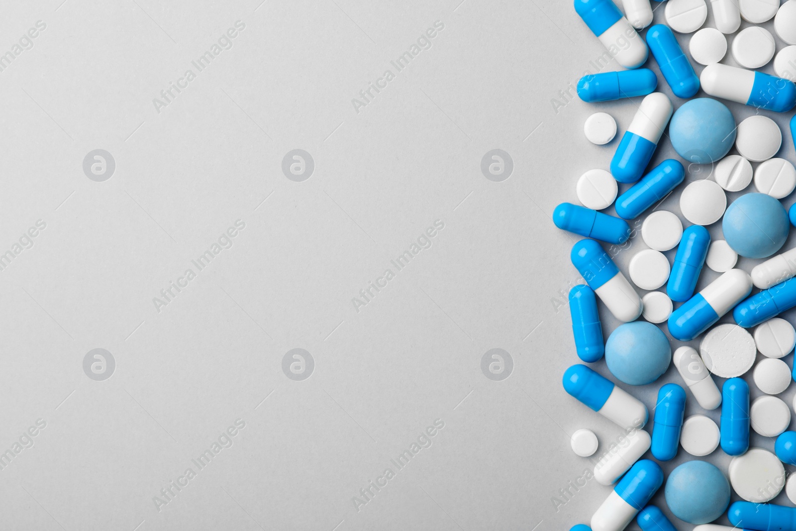 Photo of Different pills on grey background, top view. Space for text