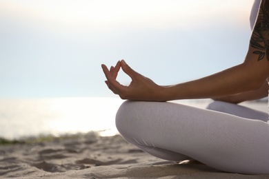 Photo of Young woman practicing zen meditation on beach, closeup. Space for text