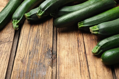 Photo of Green ripe zucchinis on wooden table, closeup. Space for text