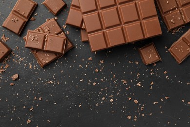 Photo of Pieces of tasty chocolate on grey table, flat lay. Space for text