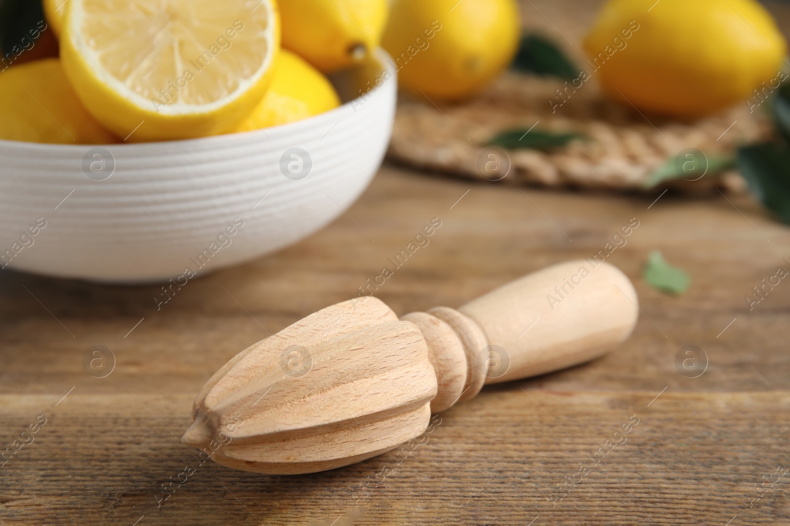 Photo of Squeezer with lemons on wooden table, closeup