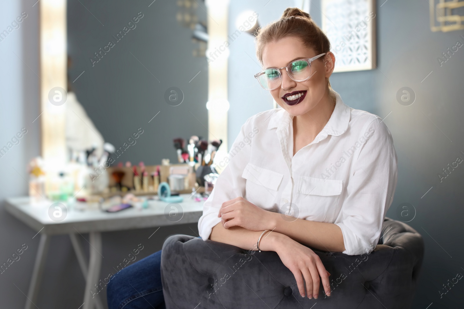 Photo of Beautiful young woman with makeup made by professional artist in dressing room