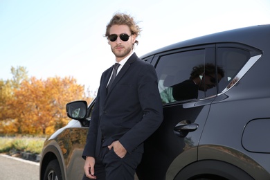 Young businessman near modern car on sunny day, outdoors