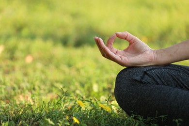 Photo of Woman meditating on green grass, closeup. Space for text
