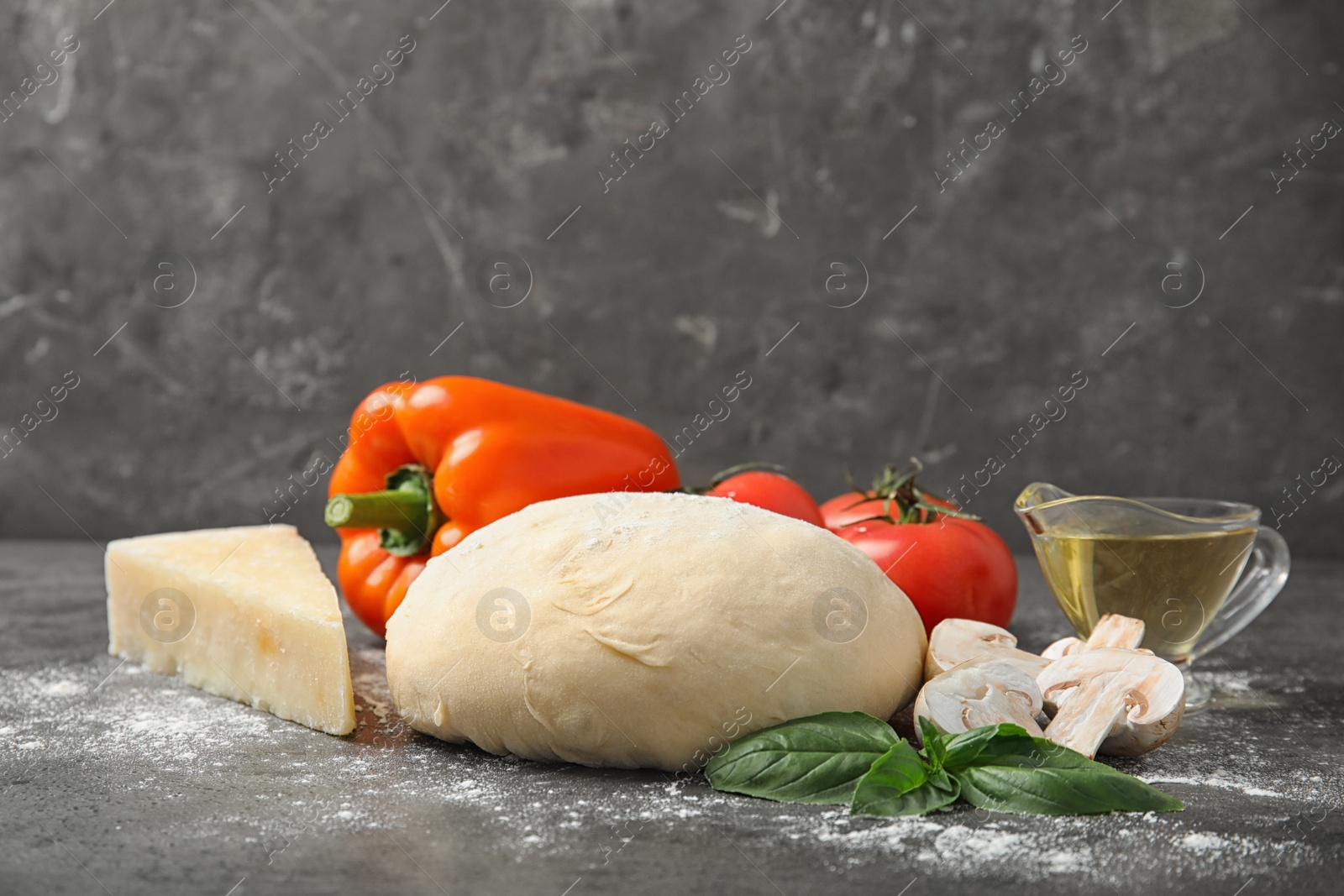 Photo of Fresh dough and ingredients for pizza on table against grey background