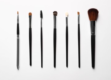 Photo of Different makeup brushes on white background, flat lay