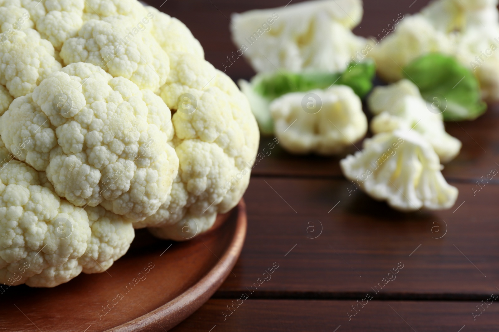 Photo of Plate with fresh raw cauliflower on wooden table, closeup. Space for text