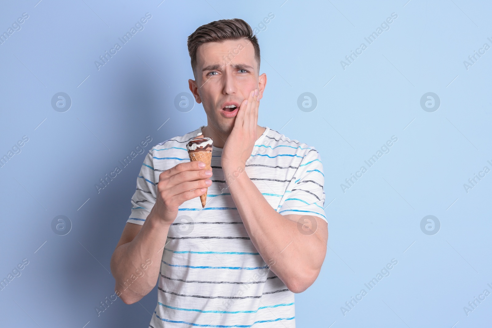 Photo of Young man with sensitive teeth and cold ice cream on color background