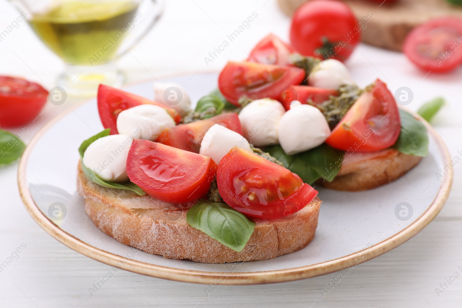 Photo of Delicious Caprese sandwiches with mozzarella, tomatoes, basil and pesto sauce on white wooden table, closeup