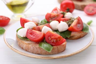 Photo of Delicious Caprese sandwiches with mozzarella, tomatoes, basil and pesto sauce on white wooden table, closeup