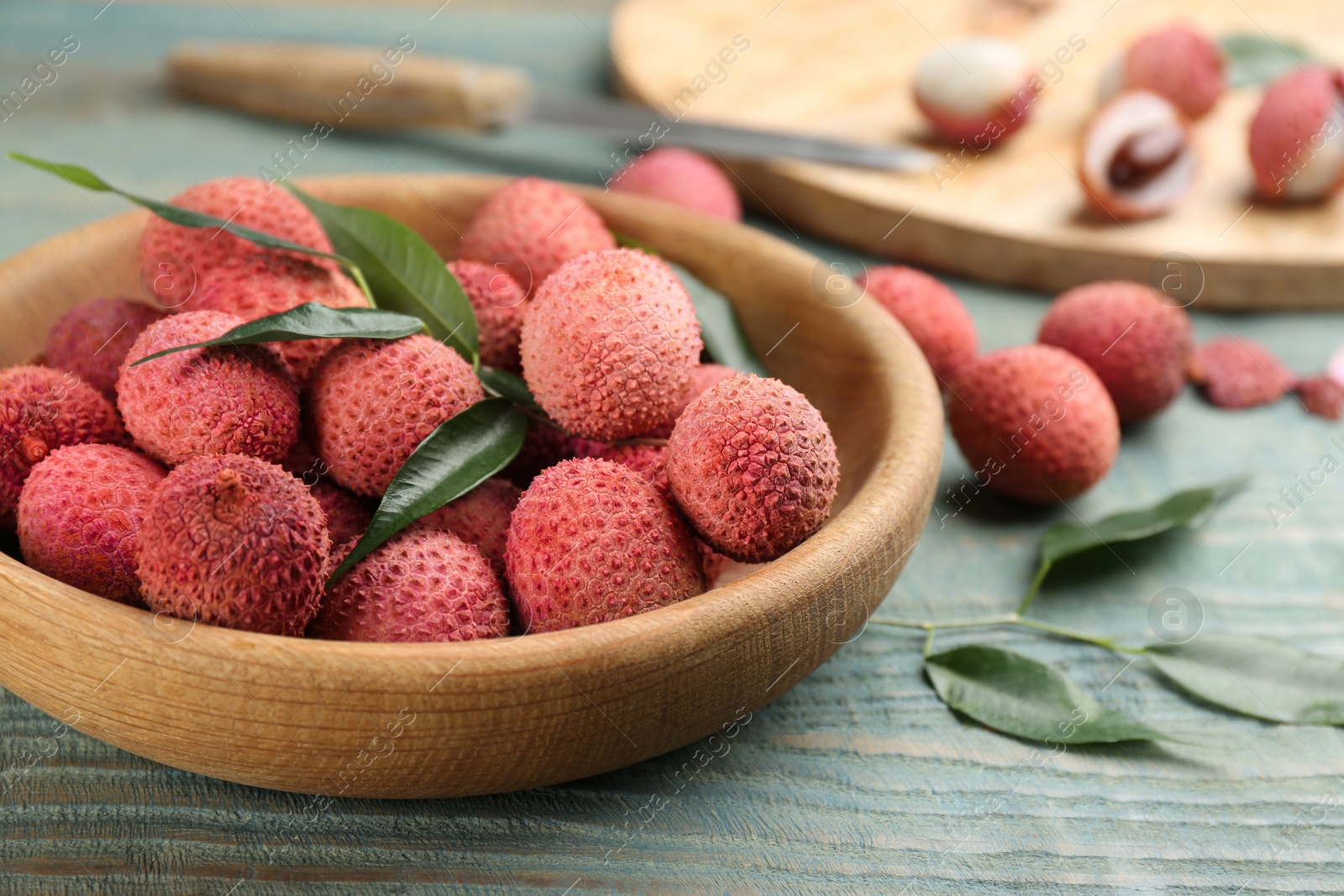 Photo of Fresh ripe lychee fruits and leaves on wooden table