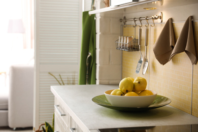 Plate with ripe quinces on countertop in kitchen. Space for text