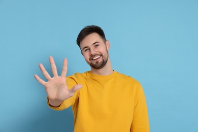 Photo of Man giving high five on light blue background