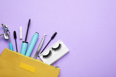 Flat lay composition with fake eyelashes, brushes and tools on lilac background. Space for text