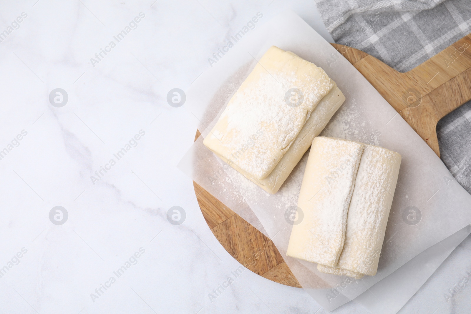 Photo of Raw puff pastry dough on white marble table, top view. Space for text