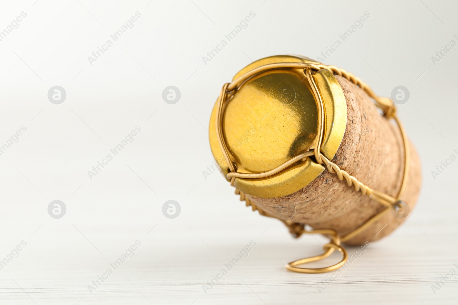 Photo of Cork of sparkling wine and muselet cap on white wooden table, closeup. Space for text