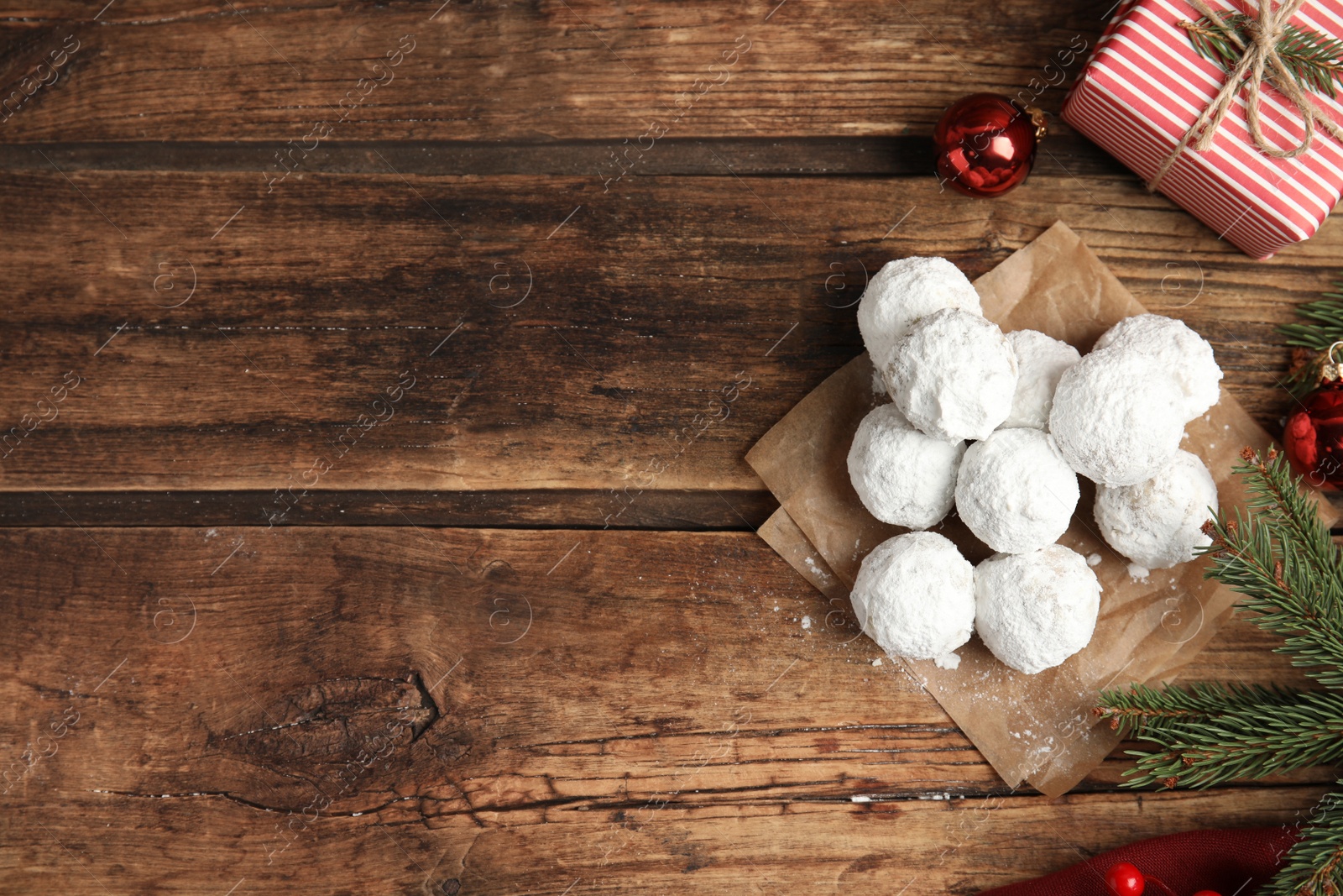 Photo of Tasty snowball cookies and Christmas decorations on wooden table, flat lay. Space for text