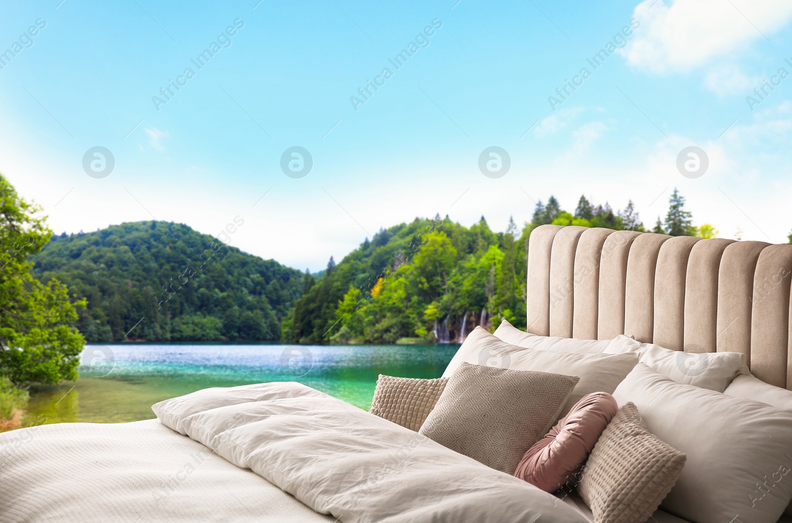 Image of Comfortable bed with soft pillows and picturesque view of river and mountains on background