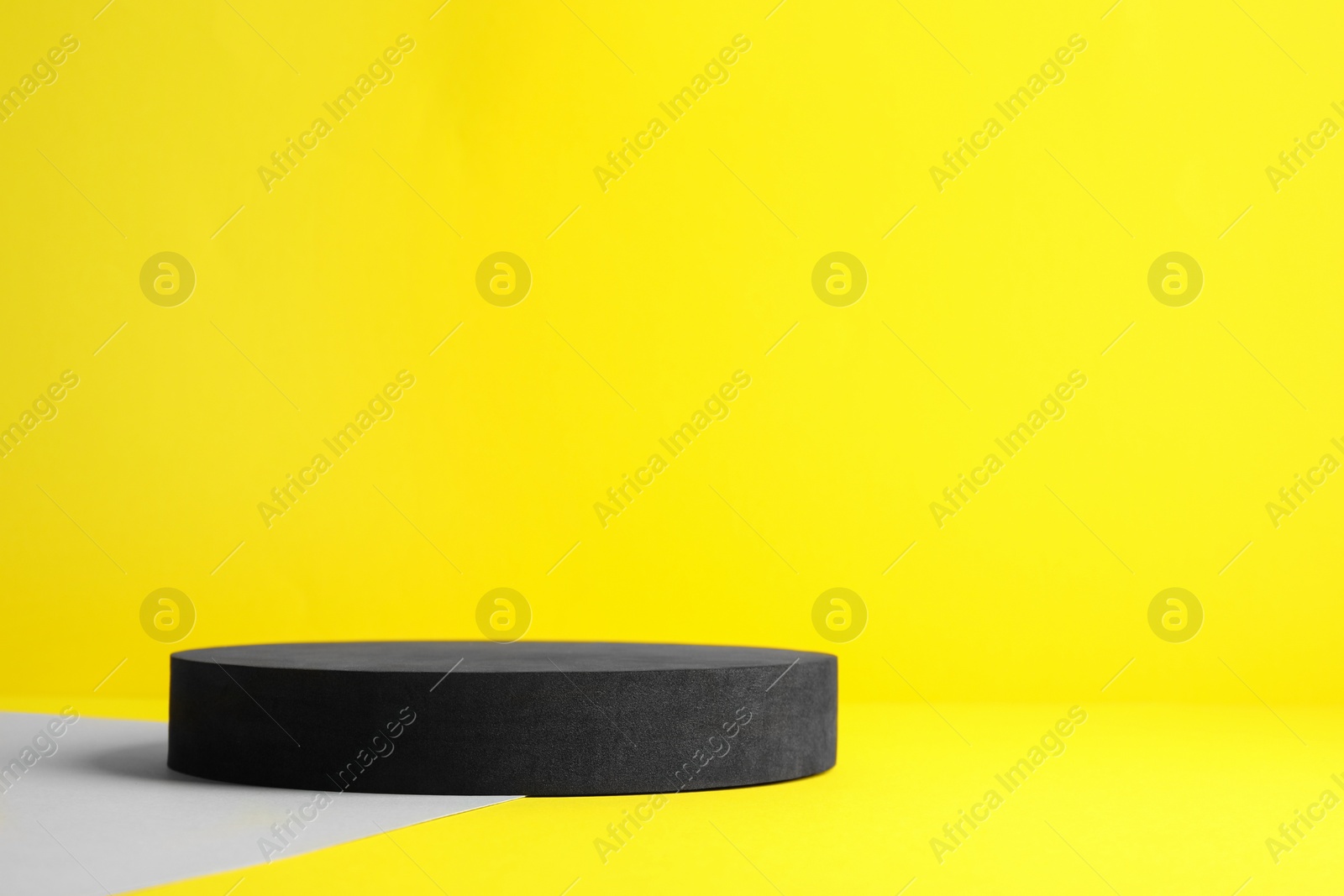 Photo of Black stand on yellow background, space for text. Stylish presentation for product