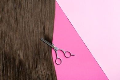 Photo of Flat lay composition with brown hair, scissors and space for text on color background