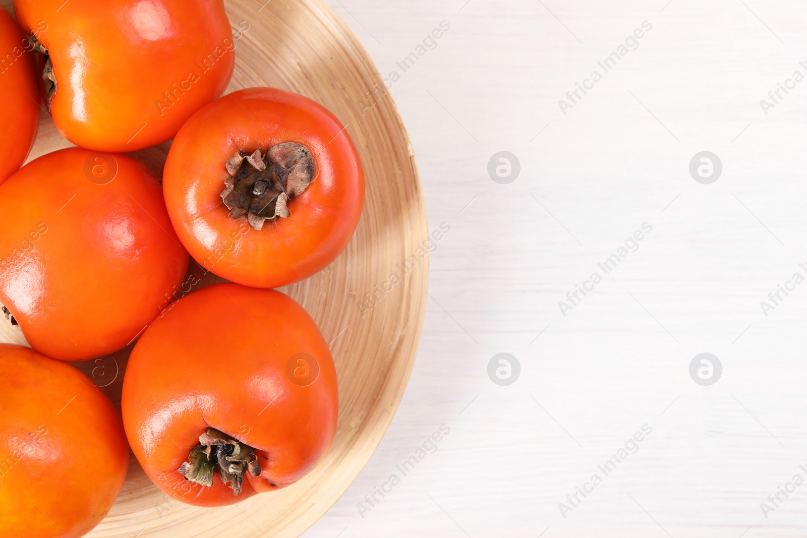 Photo of Delicious ripe persimmons on white wooden table, top view. Space for text