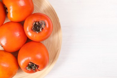 Photo of Delicious ripe persimmons on white wooden table, top view. Space for text