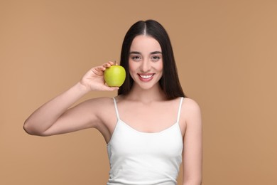 Photo of Beautiful young woman with apple on beige background
