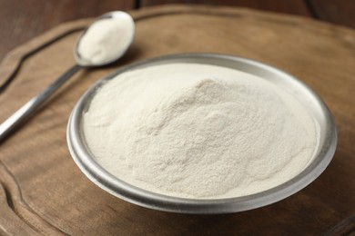 Photo of Bowl and spoon of agar-agar powder on wooden table, closeup