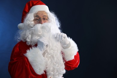 Photo of Merry Christmas. Santa Claus posing on dark blue background, space for text