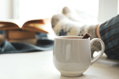 Photo of Cup of delicious mulled wine near window indoors. Winter drink