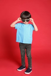 Photo of Cute little boy with sunglasses on red background