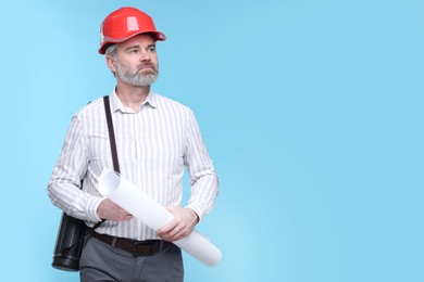 Photo of Architect in hard hat holding draft on light blue background. Space for text