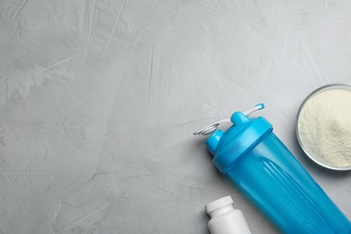 Photo of Bottle, protein powder and space for text on grey background, top view. Preparing shake