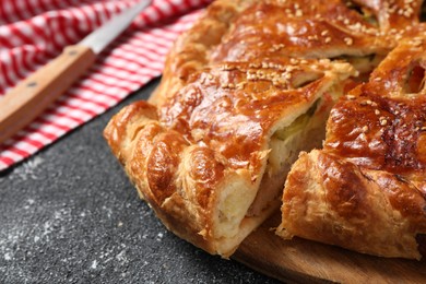Photo of Cut delicious homemade pie on black table, closeup