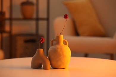 Photo of Vases with dried flowers on table in living room. Home-like cozy atmosphere at sunset