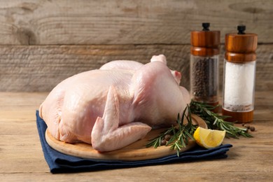 Photo of Fresh raw chicken with spices and lemon on wooden table