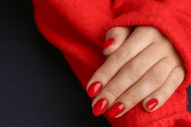 Photo of Woman with red polish on nails against black background, closeup. Space for text