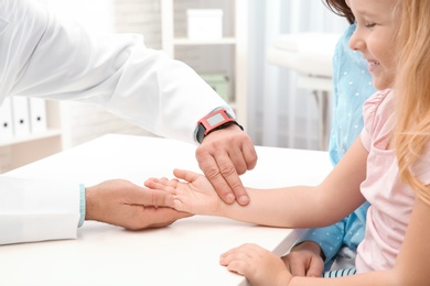 Photo of Doctor checking little girl's pulse with fingers in hospital