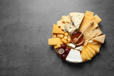 Photo of Different types of delicious cheese and snacks on served grey table, top view. Space for text
