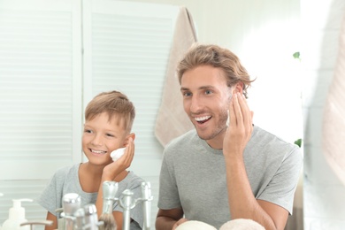 Photo of Father and son applying shaving foam in bathroom