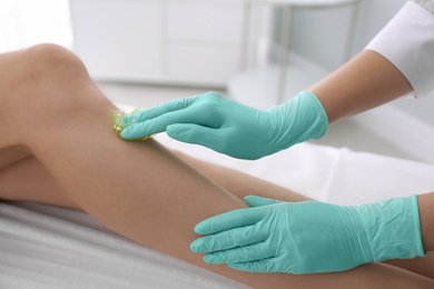 Photo of Woman getting wax epilation of legs in salon, closeup