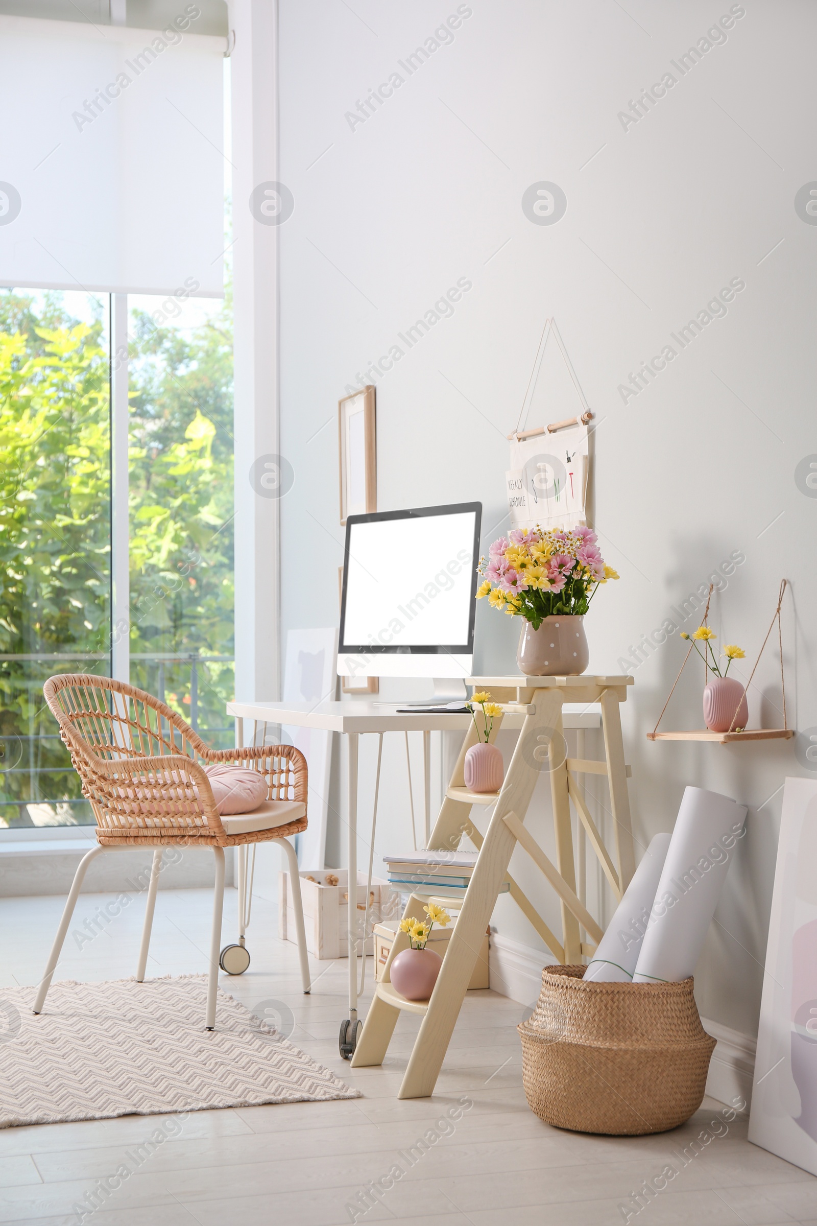 Photo of Comfortable workplace with modern computer and flowers in room. Interior design