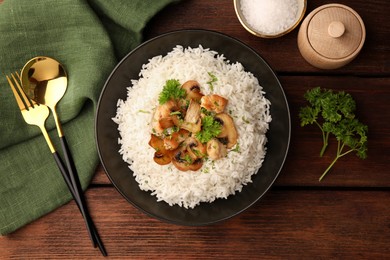 Photo of Delicious rice with mushrooms and parsley served on wooden table, flat lay