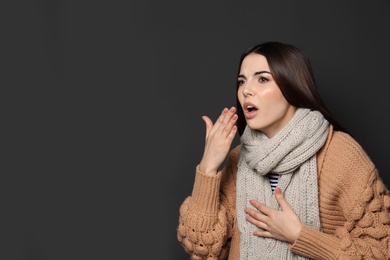 Photo of Beautiful young woman coughing against dark background. Space for text