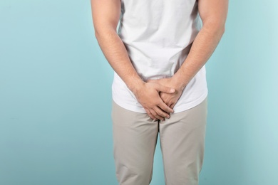 Photo of Young man with urological problems suffering from pain on color background