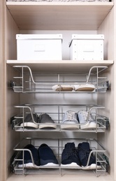 Photo of Drawers with different shoes and boxes on shelf in wardrobe closet