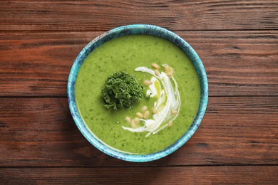 Photo of Tasty kale soup with pine nuts on wooden table, top view