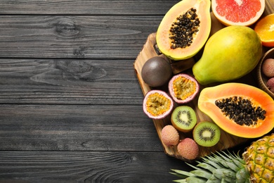 Photo of Fresh ripe papaya and other fruits on dark wooden table, flat lay. Space for text